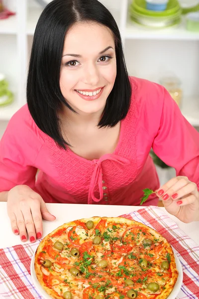 Mooi meisje met heerlijke pizza op keuken achtergrond — Stockfoto