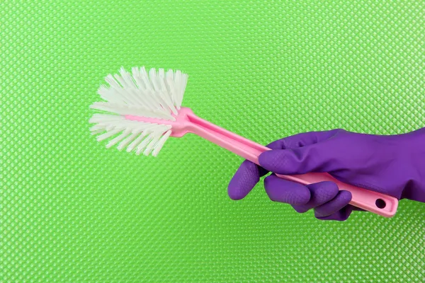 Toilet brush in hand on green background — Stock Photo, Image