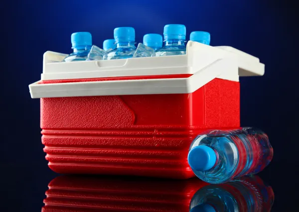 Refrigerador viajero con botellas de agua y cubitos de hielo, sobre fondo azul —  Fotos de Stock