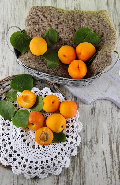 Apricots in basket on napkin on wooden table — Stock Photo, Image