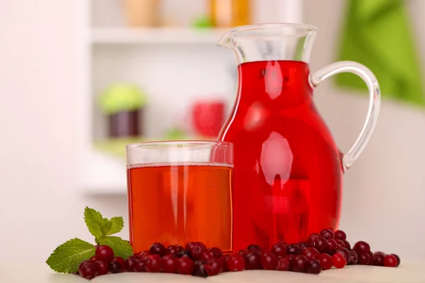 Werper en glas cranberry sap met rode veenbessen op tafel — Stockfoto