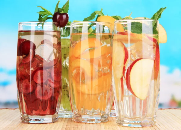 Copos de bebidas de frutas com cubos de gelo em fundo azul — Fotografia de Stock