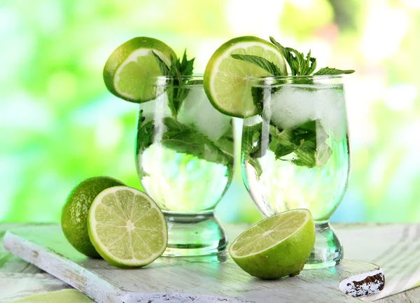 Vasos de cóctel con hielo a bordo en servilleta sobre mesa de madera sobre fondo natural — Foto de Stock