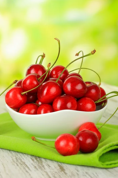 Kirschbeeren in Schale auf Holztisch auf hellem Hintergrund — Stockfoto