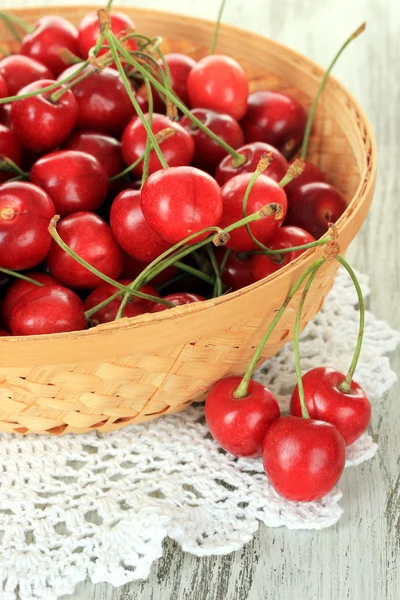 Вишневые ягоды в плетеной корзине на деревянном столе — стоковое фото