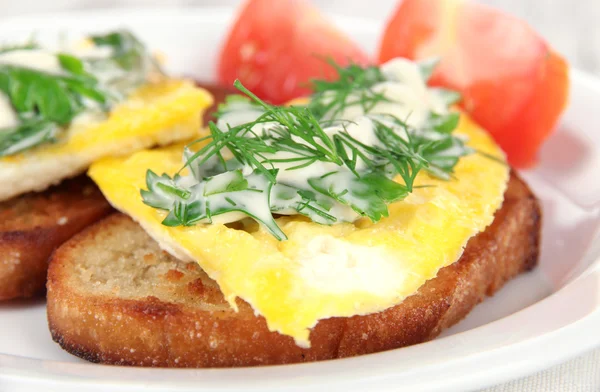 Scrambled eggs and toast on plate on napkin on wooden table — Stock Photo, Image