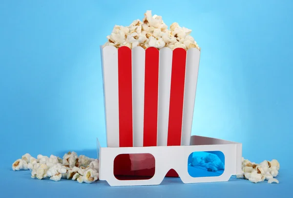 Popcorn e occhiali 3D su sfondo blu — Foto Stock