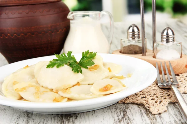 Tasty dumplings with fried onion on white plate, on bright background — Stock Photo, Image