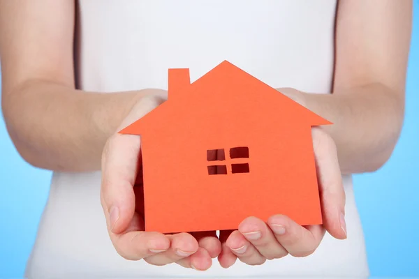 Paper house in hands on blue background — Stock Photo, Image