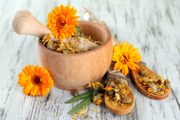 Fresh and dried calendula flowers in mortar on wooden background — Stock Photo, Image