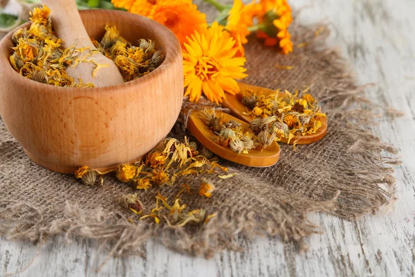 Frische und getrocknete Ringelblumen im Mörser auf Holzgrund — Stockfoto