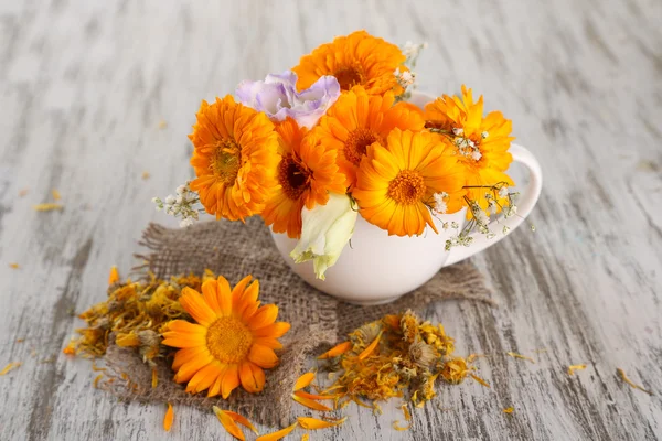 Ringelblumen in Tasse auf Holzgrund — Stockfoto