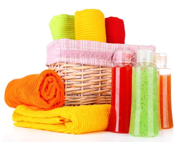 Colorful towels in basket and cosmetics bottles, isolated on white — Stock Photo, Image