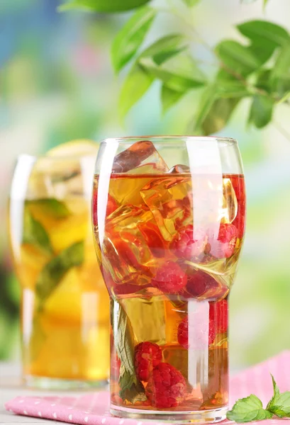 Iced tea with raspberries, lemon and mint on wooden table, outdoors — Stock Photo, Image