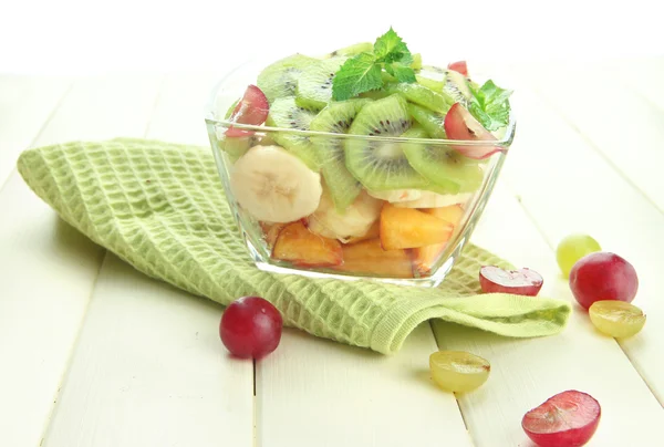 Salada de frutas saborosas em tigela de vidro, na mesa de madeira branca — Fotografia de Stock