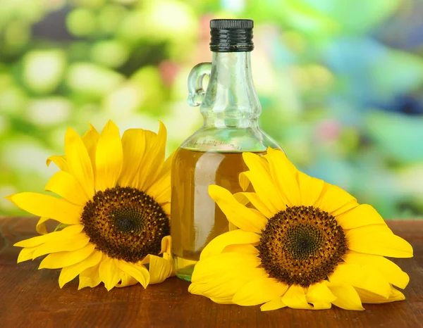 Oil in jar and sunflower on wooden table close-up — Stock Photo, Image