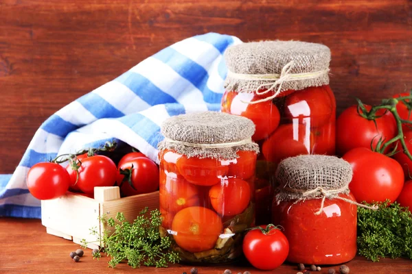 Sabrosos tomates enlatados y frescos sobre mesa de madera — Foto de Stock