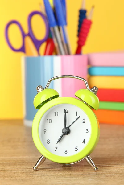 Relógio de alarme verde na mesa no fundo amarelo — Fotografia de Stock