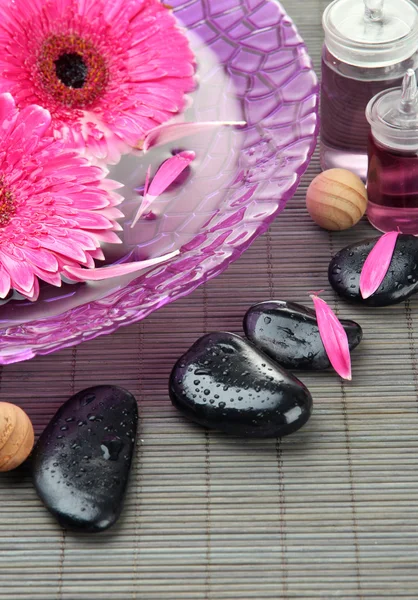 Gerbera blommor på vatten och spa stenar på bambu matta — Stockfoto
