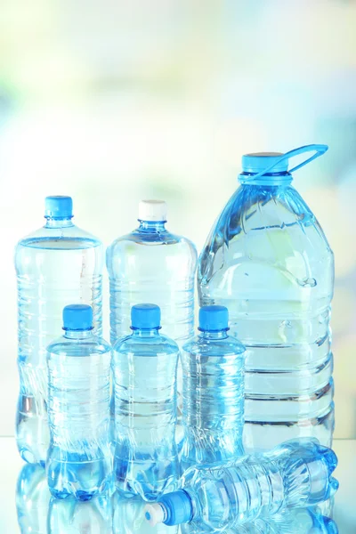 Woda w różnych butelek na jasnym tle — Zdjęcie stockowe