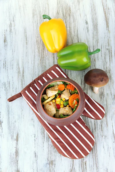 Pečené smíšené zeleniny s kuřecími prsíčky v hrnci na potholder, na dřevěné pozadí — Stock fotografie