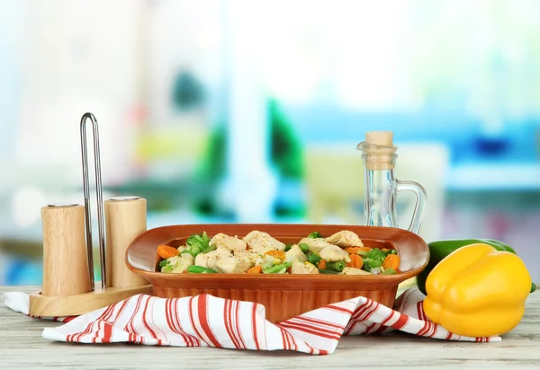 Casserole with vegetables and meat, on wooden table, on bright background — Stock Photo, Image