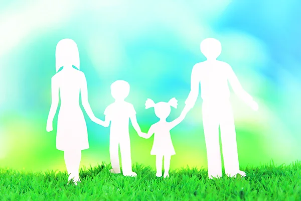 Familie aus Papier auf Gras auf hellem Hintergrund — Stockfoto