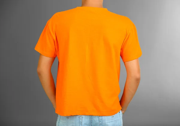 T-Shirt auf jungem Mann, auf grauem Hintergrund — Stockfoto