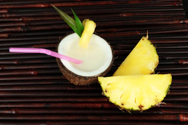 Bebida de piña colada en coco, sobre fondo de estera de bambú —  Fotos de Stock