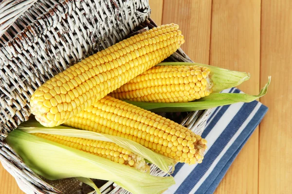 Crude corns in basket on napkin on wooden table — Stock Photo, Image