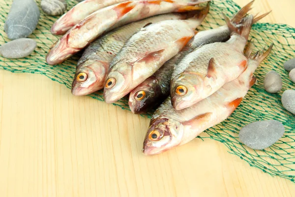 Fishes on fishing net on wooden background — Stock Photo, Image