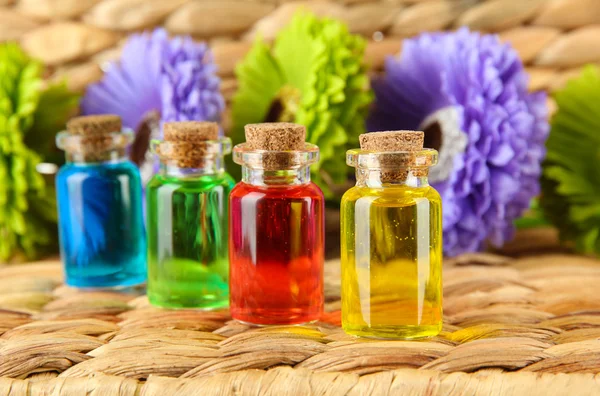 Bottles with colored liquids on wicker wooden background — Stock Photo, Image