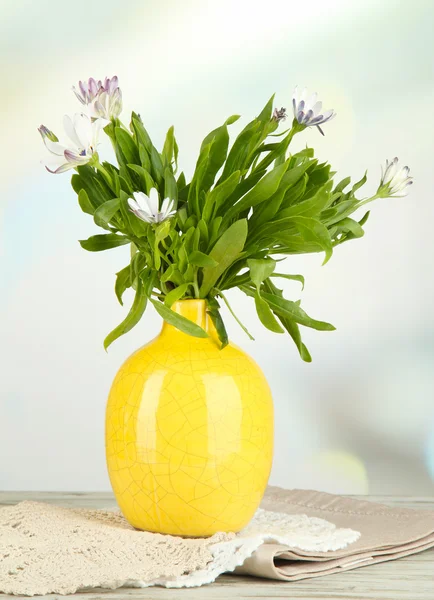 Ramillete de hermosas flores de verano en jarrón de color, sobre mesa de madera, sobre fondo brillante —  Fotos de Stock