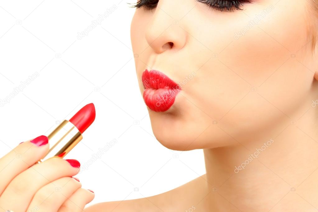 beautiful woman is applying her lips with red lipstick