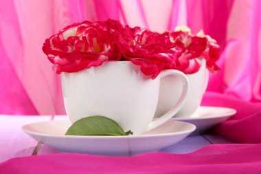 gül pembe kumaş zemin üzerine ahşap masa üstünde CUPS