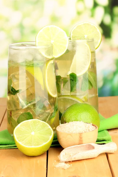 Glasses of cocktail with lime and mint on wooden table on bright background — Stock Photo, Image