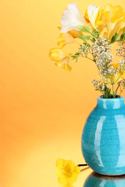 Mooi boeket van fresia's in vaas op oranje achtergrond — Stockfoto