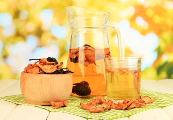 Assorted dried fruits in bowl and compote of dried fruits on wooden table on natural background — Stock Photo, Image