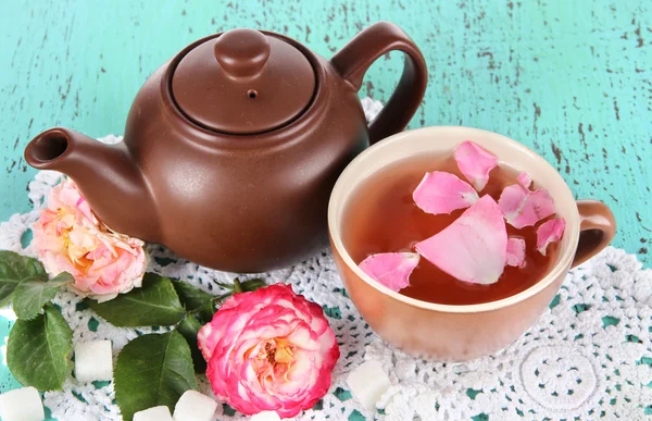 Vattenkokare och kopp te från tea rose ombord på servett på trä bakgrund — Stockfoto