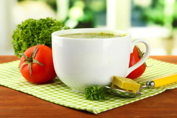 Copa de sopa con cubos de caldo sobre mesa de madera — Foto de Stock