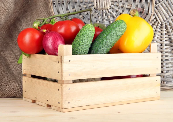 Свежие овощи в деревянной коробке на плетеном фоне — стоковое фото