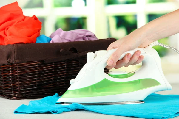 Woman's hand ironing clothes, on bright background — Stock Photo, Image