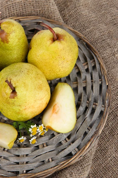 Pears on braided tray on burlap on wooden table — Stock Photo, Image