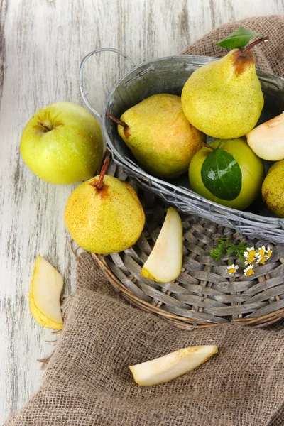 Pears in basket on braided tray on burlap on wooden table — Stock Photo, Image