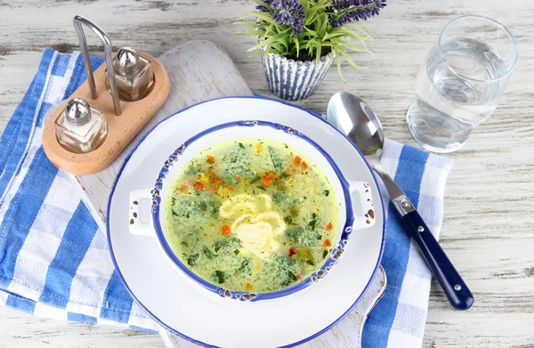 Soup in plate on napkin on wooden board on table — Stock Photo, Image