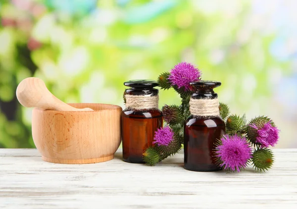 Botellas de medicina y mortero con flores de cardo sobre fondo natural —  Fotos de Stock