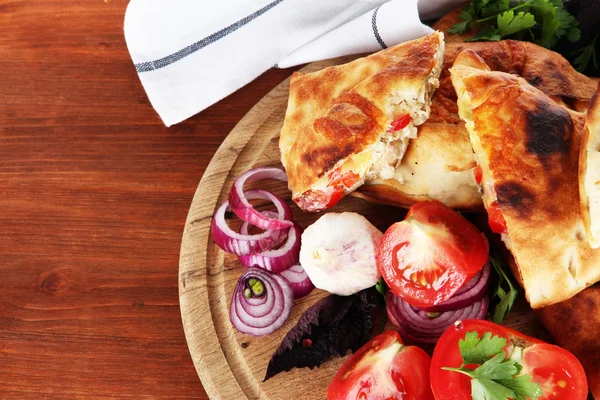 Calzones de pizza em tábua de madeira perto de guardanapo em mesa de madeira — Fotografia de Stock