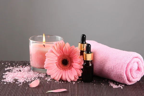 Beautiful pink candle with flower and towel on bamboo mat — Stock Photo, Image