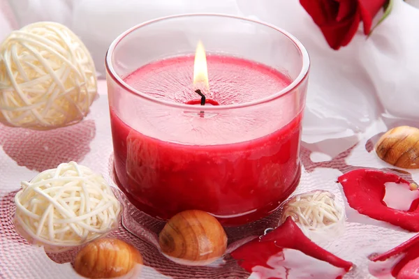 Hermosa vela roja con pétalos de flores en agua — Foto de Stock