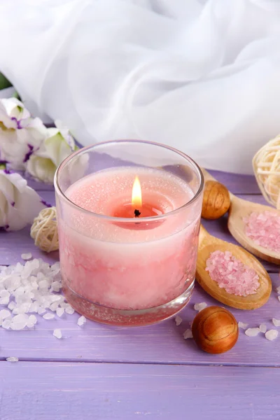 Piękny różowy świeca z kwiatami na fioletowym tle drewniane — Zdjęcie stockowe